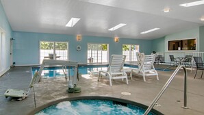 An indoor swimming pool with multiple lounge chairs and a changing room.