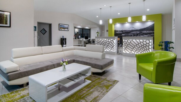 A modern living room with a sectional sofa, a white coffee table, and a bright green armchair.