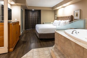 A hotel room with a bed, a bathroom with a bathtub, a wooden dresser, and a television. - Royal Hotel West Edmonton, Trademark Collection by Wyndham (Edmonton)