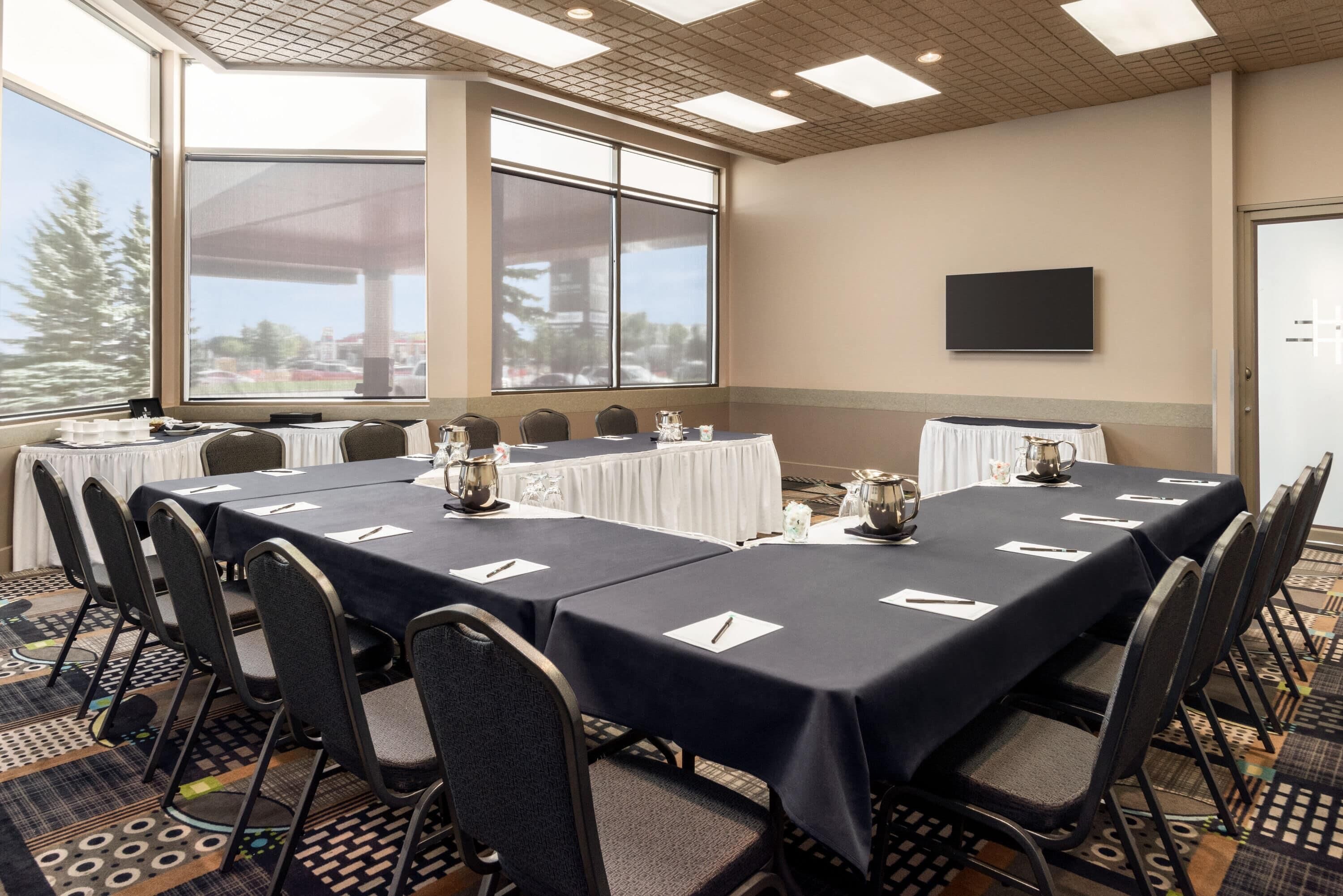 A conference room with a long table, chairs, and a TV on the wall.