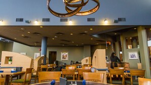 A restaurant with round tables, blue napkins, and a unique metal chandelier. - Royal Hotel West Edmonton, Trademark Collection by Wyndham (Edmonton)