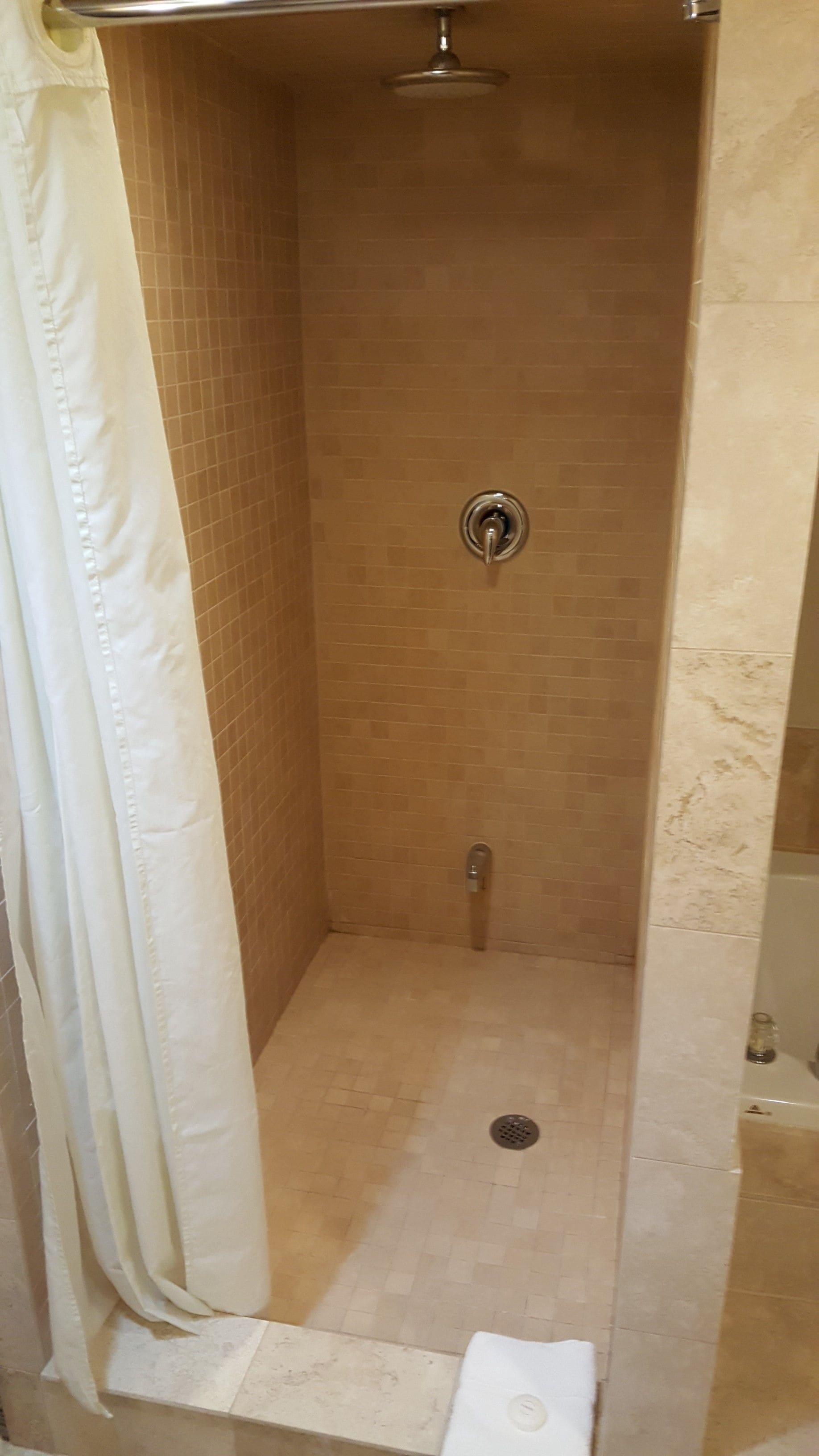 Une cabine de douche avec un sol carrelé et un pommeau de douche.