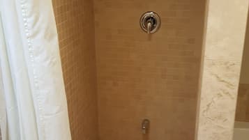 Une cabine de douche avec un sol carrelé et un pommeau de douche.