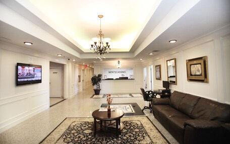 A hotel lobby with a reception desk, a television, a chandelier, a sofa, and a coffee table.