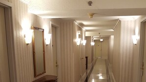 Un couloir d’hôtel aux murs recouverts de miroirs, agrémenté d’appliques murales et doté d’un sol carrelé poli.