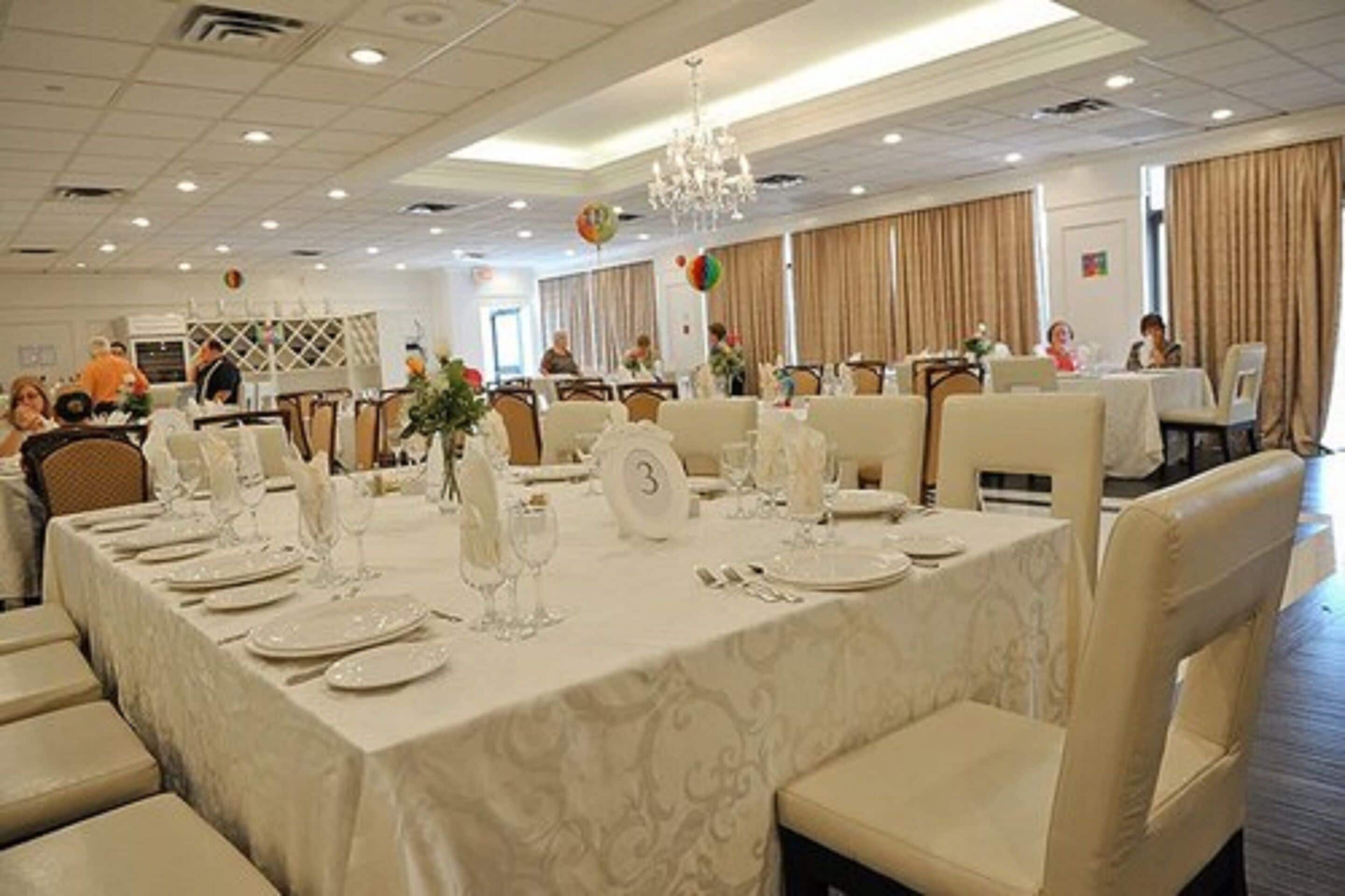 A banquet hall with tables set for dining, numbered seating, and a chandelier.