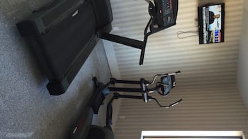 A home gym with a treadmill and an elliptical machine.