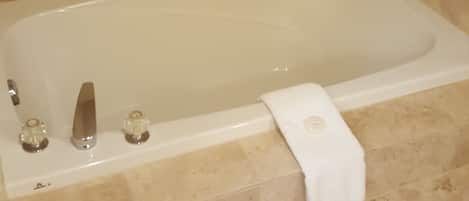 A bathroom with a bathtub, a towel rack, and a shower area.