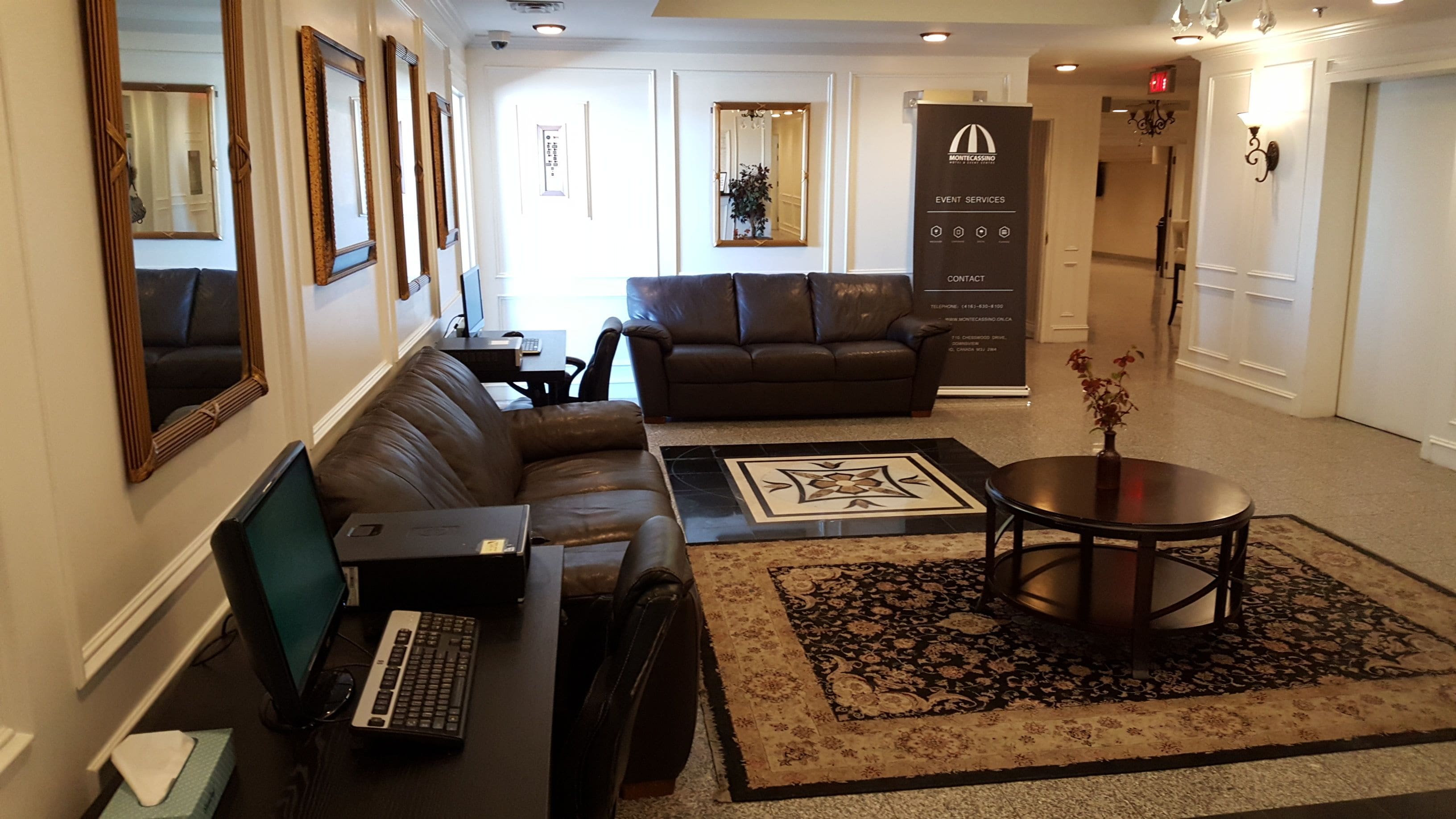 Un moderno vestíbulo de hotel con sofás de cuero, un mostrador de recepción, una computadora y una alfombra decorativa.