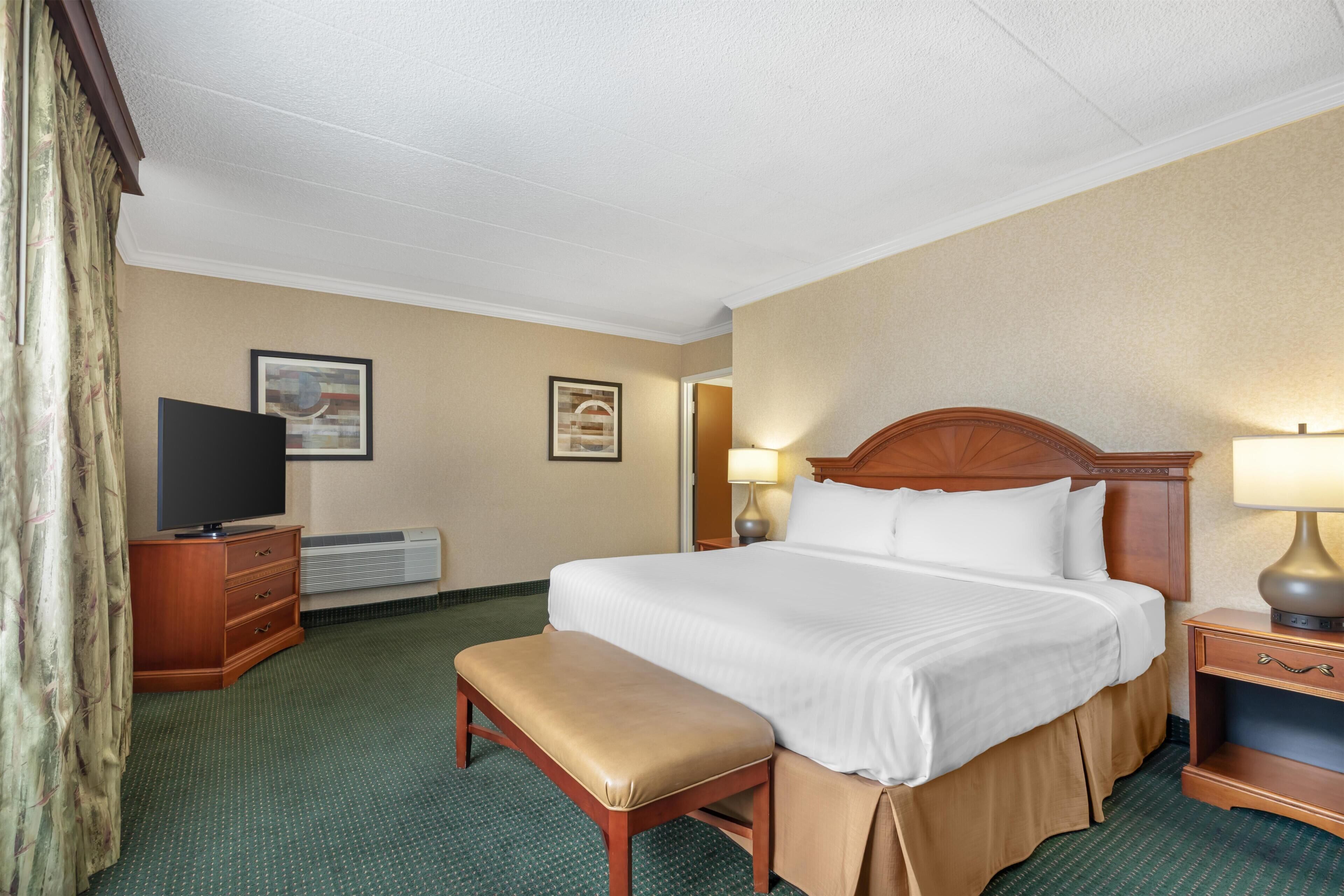 A hotel room with a bed, a television, a desk, and a lamp.