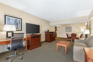Habitación de hotel con escritorio, silla, televisor, cómoda y sofá.