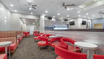 A hotel lobby with red seating, ceiling fans, recessed lighting, and a patterned wall.