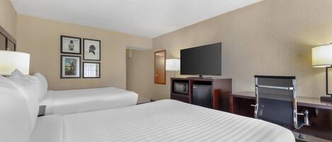 A hotel room with two beds, a flat-screen TV, a desk with a chair, and a microwave.