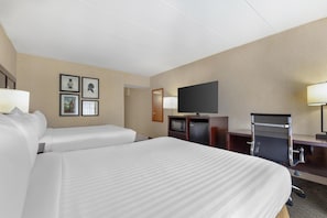 Habitación de hotel con dos camas, un televisor de pantalla plana, un escritorio con una silla y un microondas.