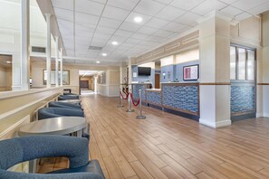 Un vestíbulo de hotel con una recepción, zona de estar y un pasillo que conduce a otras habitaciones.