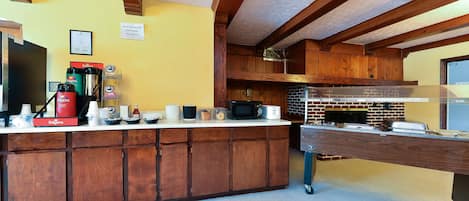 A kitchen with wooden cabinets, a countertop with various appliances, and a brick oven.