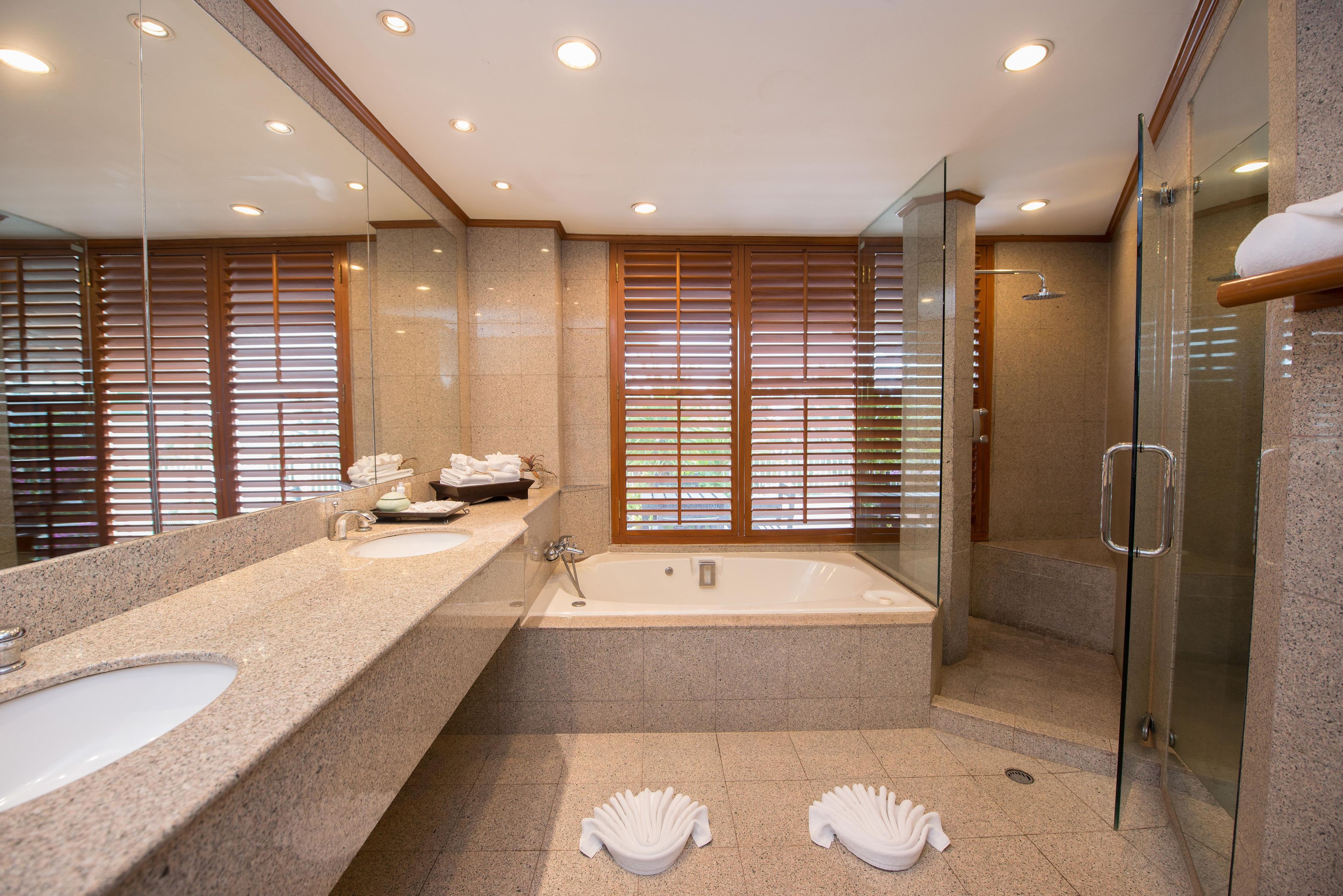 A modern bathroom with a double sink, a bathtub, and a glass-enclosed shower area.