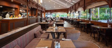 A spacious restaurant with high ceilings, wooden paneling, and large windows offering a view of the outdoors.