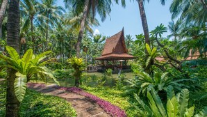 A tropical resort with a traditional thatched-roof structure surrounded by lush greenery and palm trees. - Avani Pattaya Resort (Pattaya)