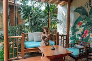 A wooden deck with a blue sofa, a wooden table, and chairs. - Avani Pattaya Resort (Pattaya)