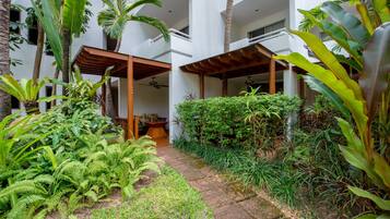 A courtyard with lush greenery, including ferns and palm trees, and a stone pathway.
