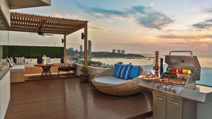 A rooftop terrace with a grill, seating area, and a view of the city skyline. - Avani Pattaya Resort (Pattaya)