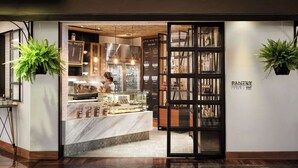 A bakery with a coffee machine, display case, and hanging plants. - Avani Pattaya Resort (Pattaya)