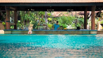 A pool area with a covered seating area and a bar.