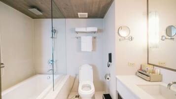 A modern bathroom with a glass shower enclosure, a bathtub, a toilet, and a vanity with a mirror.