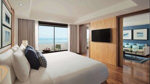 A hotel room with a large bed, a TV, a view of the ocean, and a balcony with a sofa and table. - Avani Pattaya Resort (Pattaya)