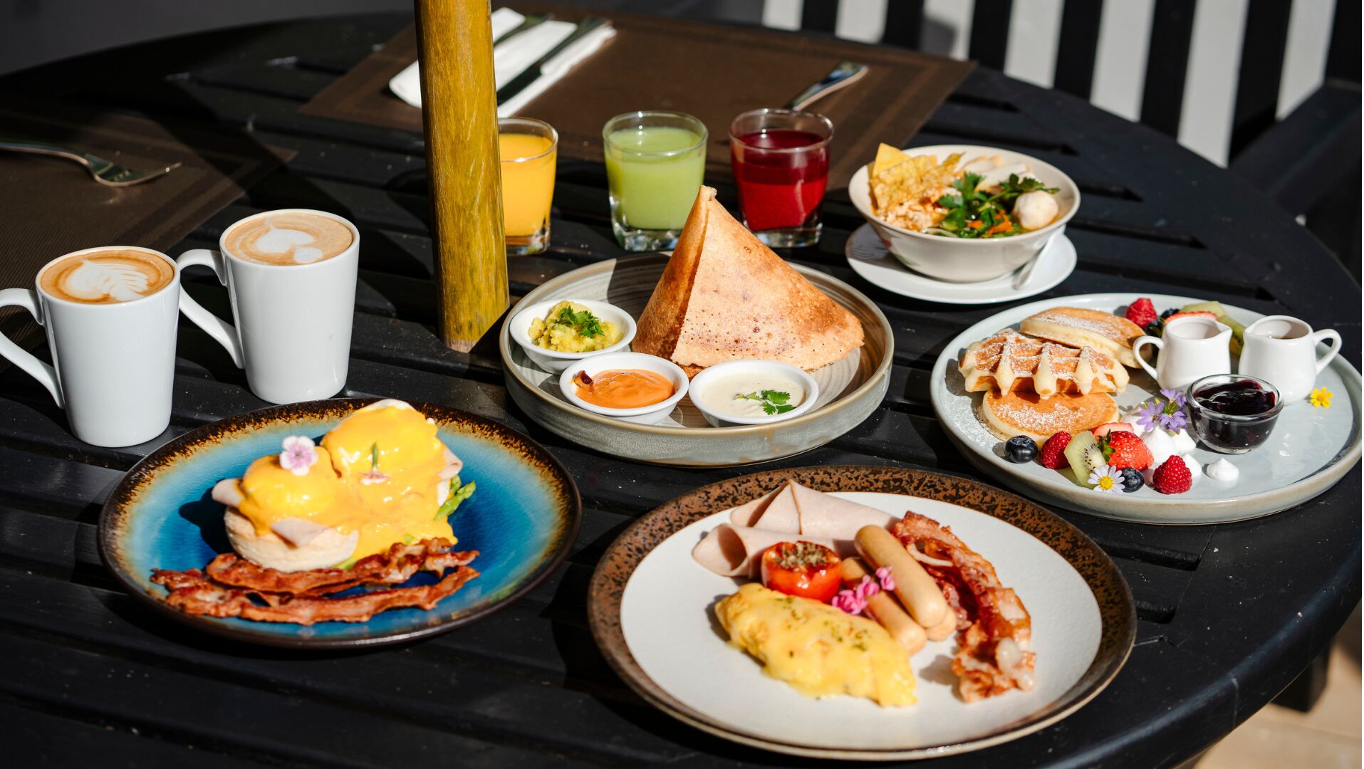 Une table de petit-déjeuner avec divers plats, notamment des œufs, du bacon, des toasts et des fruits.