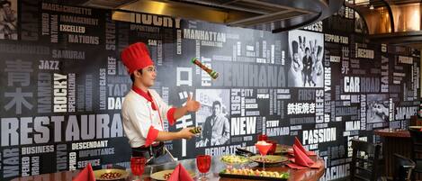 A chef at a counter with a word cloud backdrop, a bottle, and a plate of food.
