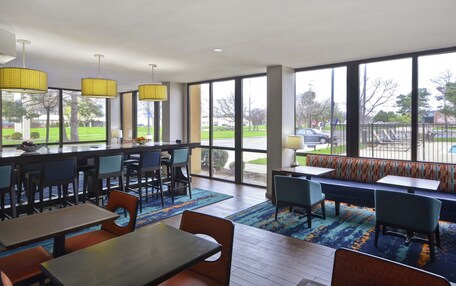 A modern hotel lobby with a bar area, seating, and large windows offering a view of the outdoors.