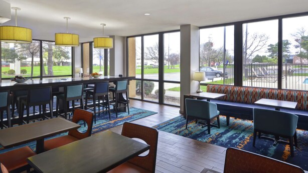 A modern hotel lobby with a bar area, seating, and large windows offering a view of the outdoors. - Hampton Inn Detroit/Madison Heights/South Troy (Madison Heights)
