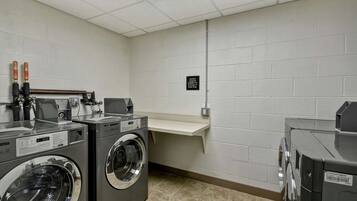 A laundry room with two front-loading washers, a dryer, and a bench.