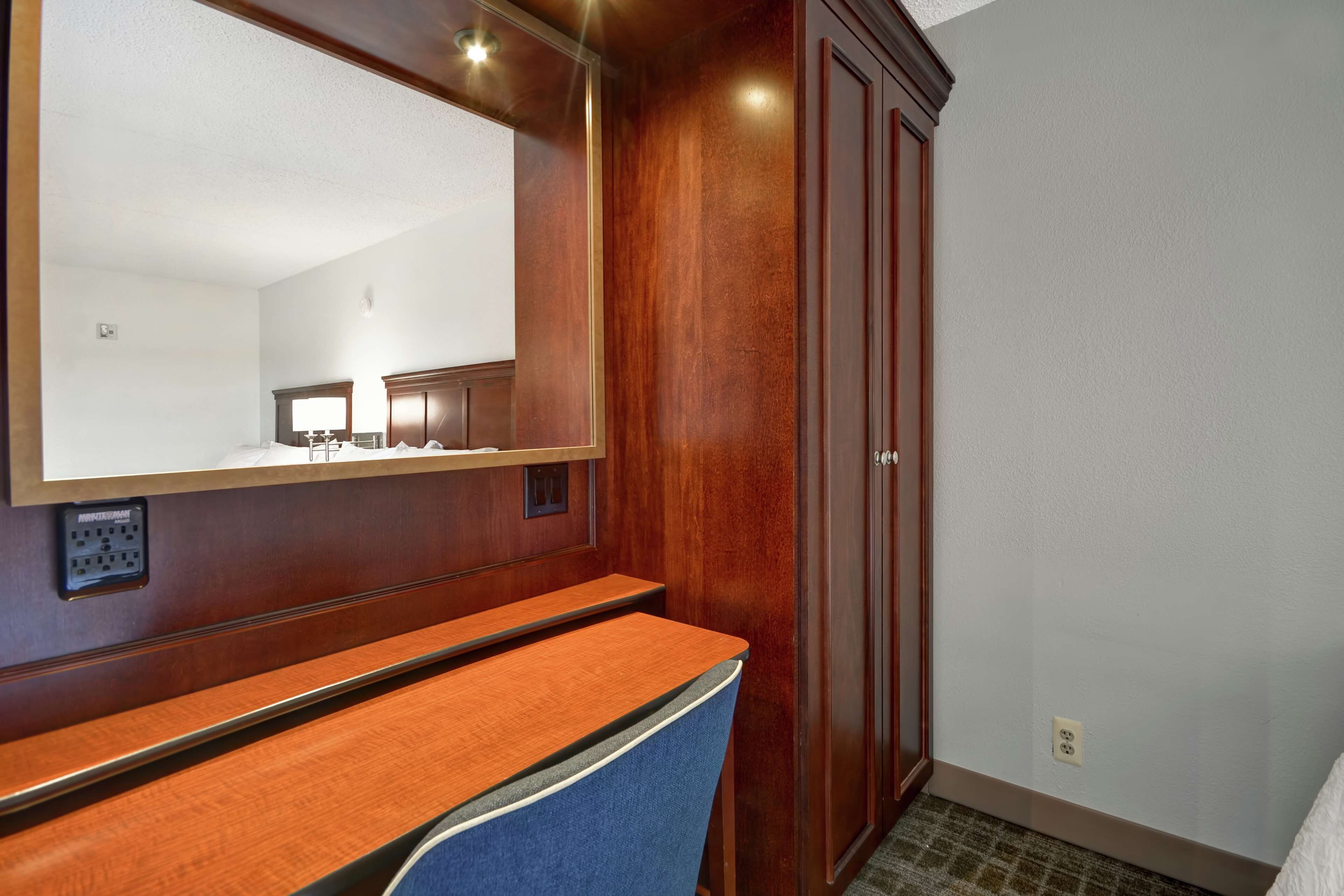 Un baño de hotel con tocador de madera, espejo y armario.