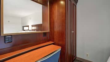 Un baño de hotel con tocador de madera, espejo y armario.