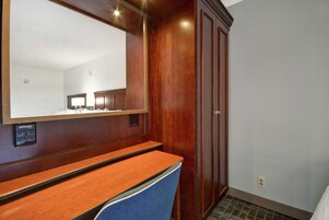 Un baño de hotel con tocador de madera, espejo y armario.