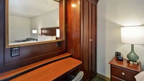 A hotel room with a wooden desk, a mirror, a bedside lamp, and a nightstand. - Hampton Inn Detroit/Madison Heights/South Troy (Madison Heights)