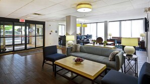 A hotel lobby with a reception desk, seating area, and large windows. - Hampton Inn Detroit/Madison Heights/South Troy (Madison Heights)