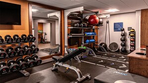 Un gimnasio con equipo de levantamiento de pesas, una prensa de banca y un espejo.