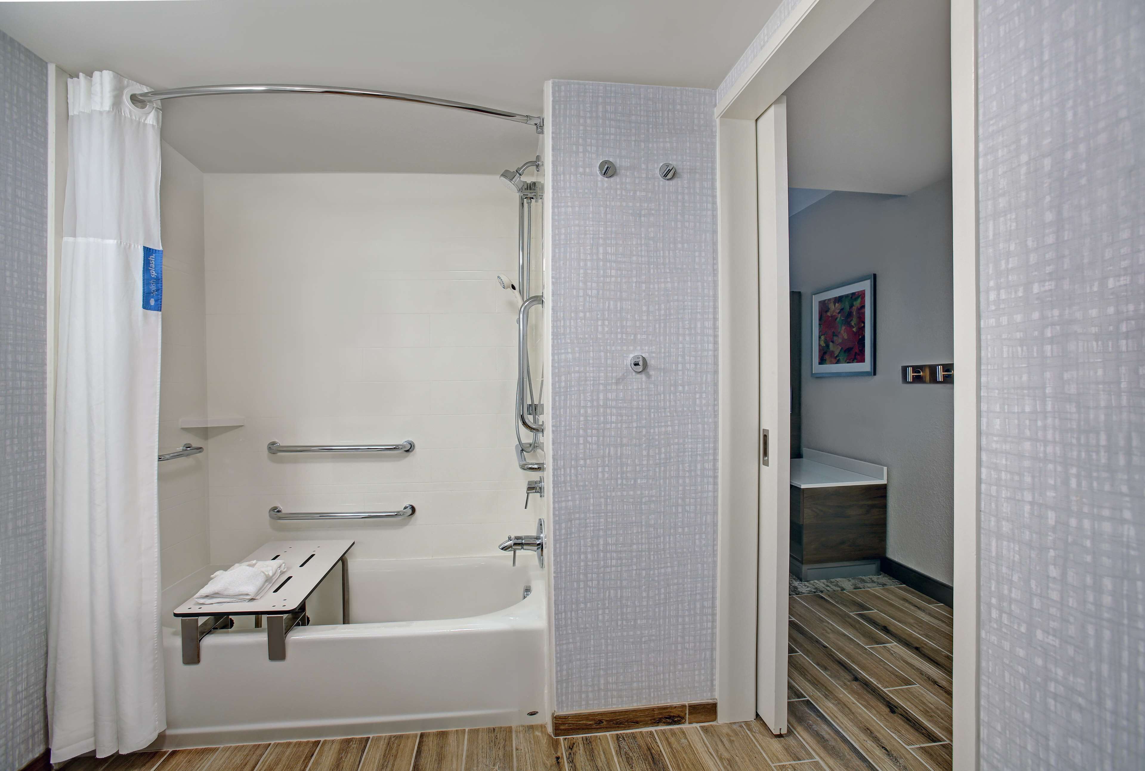 A modern bathroom with a walk-in shower, grab bars, and a towel rack.