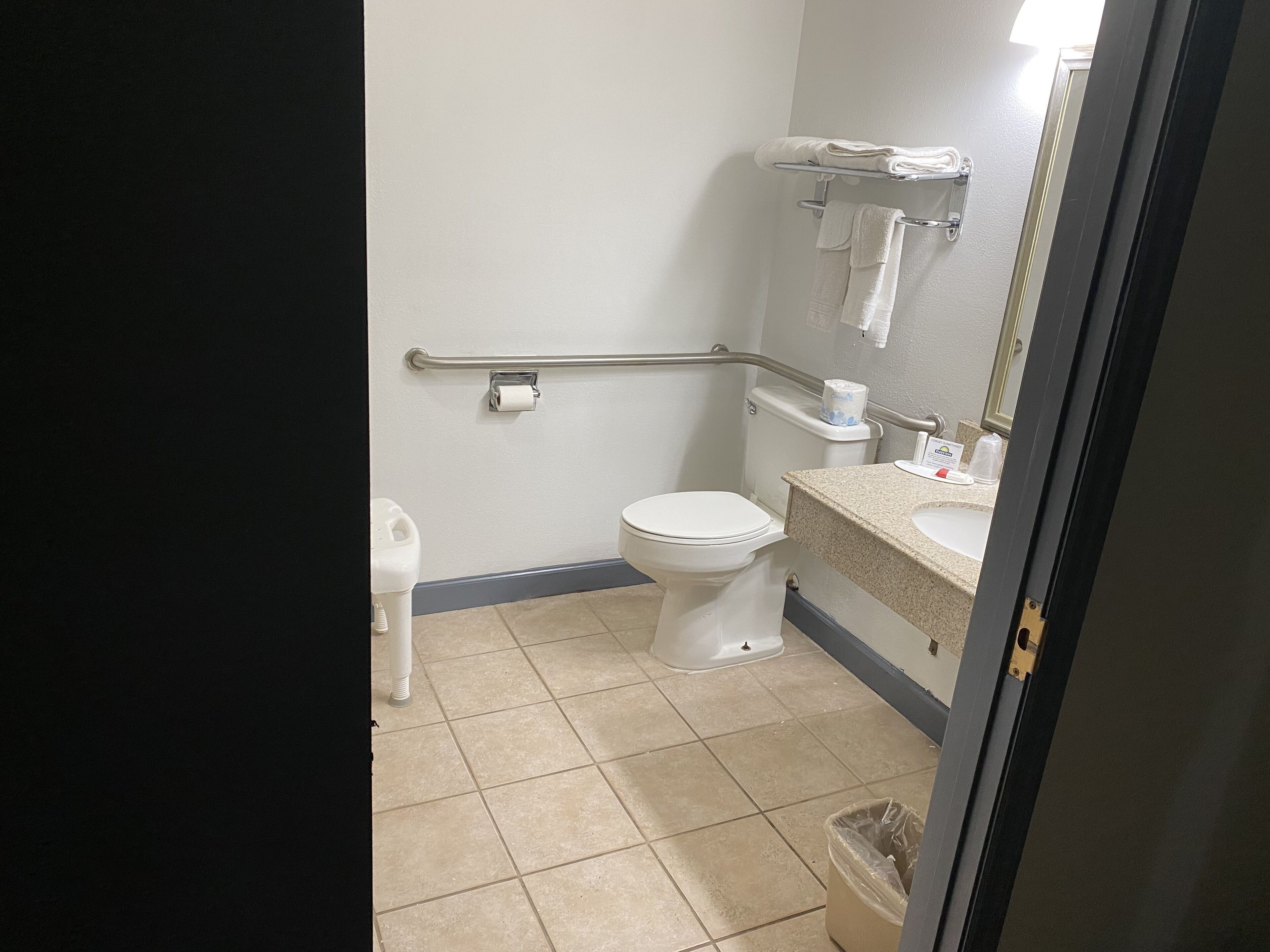 A standard hotel bathroom with a toilet, hand dryer, and a trash bin.