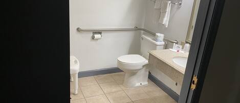Un baño de hotel estándar con inodoro, secador de manos y un cubo de basura.