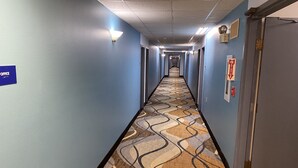 A hotel hallway with a patterned carpet, blue walls, and a sign indicating an office. - Days Inn by Wyndham Perryville (Perryville)
