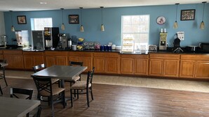 A kitchen with wooden cabinets, a dining area with a table and chairs, and various kitchen appliances. - Days Inn by Wyndham Perryville (Perryville)
