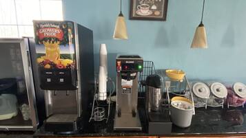A coffee station with a coffee machine, a juice dispenser, and a coffee cup.