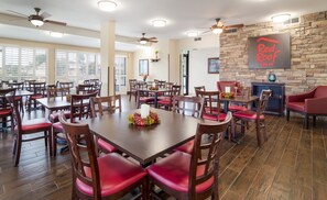 A dining area with multiple tables and chairs, a stone wall, and a sign that reads 'Red Roof Inn'. - Red Roof Inn Augusta - Washington Road (Augusta)