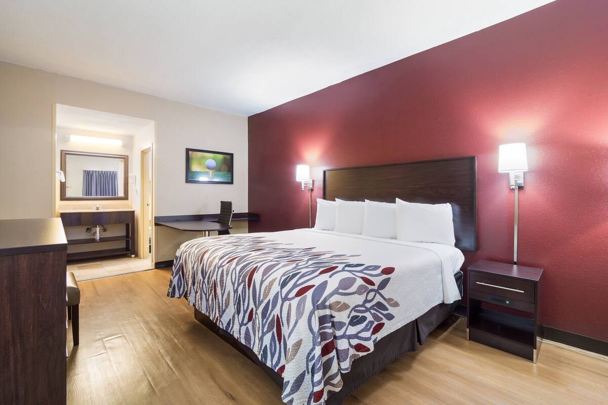 A hotel room with a bed, bedside tables, a desk, and a chair.