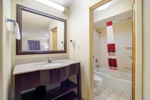 A bathroom with a sink, mirror, and a shower area. - Red Roof Inn Augusta - Washington Road (Augusta)